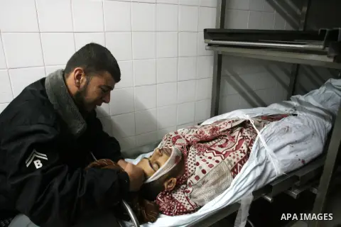 A Palestinian looks at the body of Yasser Al Attal in hospital morgue following an Israeli airstrike in area "Al fokhari" in east of Khan Younis in the southern Gaza Strip, on October 14, 2012. An Israeli air strike Satu...