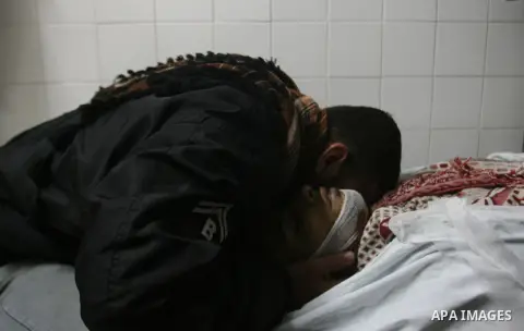 A Palestinian looks at the body of Yasser Al Attal in hospital morgue following an Israeli airstrike in area "Al fokhari" in east of Khan Younis in the southern Gaza Strip, on October 14, 2012. An Israeli air strike Satu...