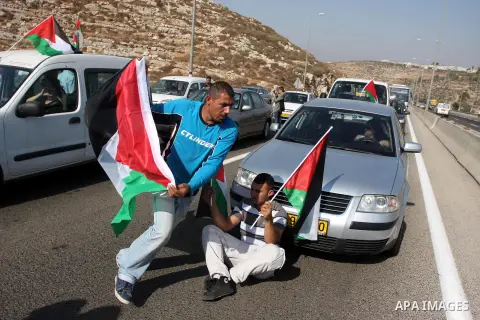 Activists hold Palestinian flags in front of Israeli troops during a protest on highway 443 near the West Bank village of Beit Ur against what they say are attacks by Jewish settlers on Palestinians and their property, O...