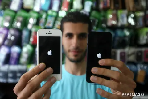 A Palestinian man holds Apple's new iPhone 5 at a mobile phone store in Gaza City on October 16, 2012. Apple's new iPhone 5 is selling well in the Gaza Strip despite inflated prices, reaching the Palestinian enclave via...