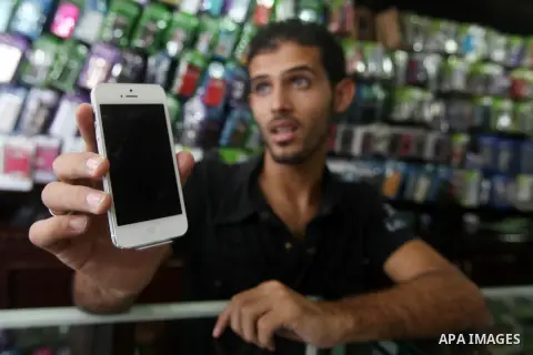 A Palestinian man holds Apple's new iPhone 5 at a mobile phone store in Gaza City on October 16, 2012. Apple's new iPhone 5 is selling well in the Gaza Strip despite inflated prices, reaching the Palestinian enclave via...