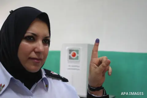 A Palestinian police officer shows her ink-stained finger after casting an early vote during local elections at a polling station in the West Bank town of Ramallah, 18 October 2012. The polling stations will be open from...