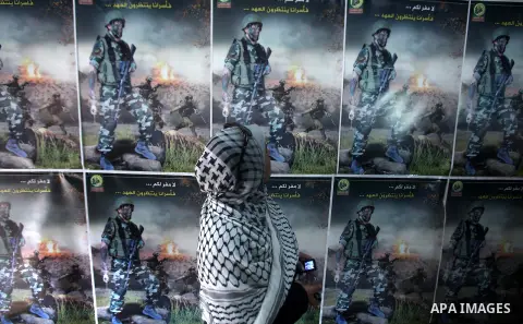 A Palestinian woman walks pass next to portrait during a ceremony to mark the first anniversary of a deal which saw the exchange of 1,027 Palestinian prisoners for captured Israeli soldier Gilad Shalit, in Gaza city on 1...
