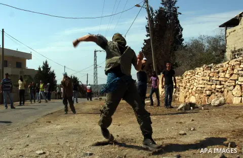 A Palestinian protester throws stones on towards Israeli soldiers during clashes following a demonstration against the expropriation of Palestinian land by Israel in the village of Kfar Qaddum, near the occupied West Ban...