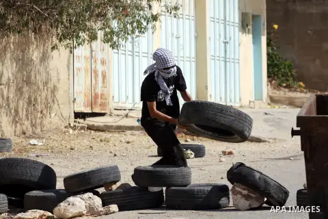A Palestinian protester carries a tire to burn it during clashes with Israeli soldiers following a demonstration against the expropriation of Palestinian land by Israel in the village of Kfar Qaddum, near the occupied We...