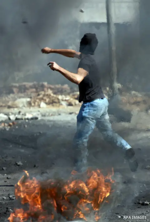 A Palestinian protester throws stones on towards Israeli soldiers during clashes following a demonstration against the expropriation of Palestinian land by Israel in the village of Kfar Qaddum, near the occupied West Ban...