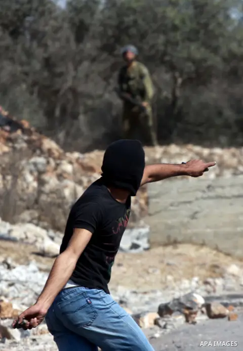 A Palestinian protester throws stones on towards Israeli soldiers during clashes following a demonstration against the expropriation of Palestinian land by Israel in the village of Kfar Qaddum, near the occupied West Ban...