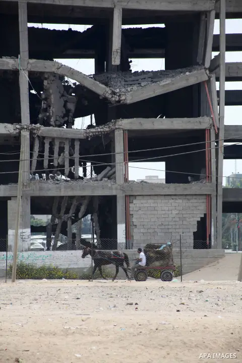 Palestinians ride their cart pass a destroyed government's building in Gaza city on October 21, 2012. A Qatari delegation headed by Ambassador Mohammed al-Emadi has arrived in Gaza through the Rafah crossing to monitor p...
