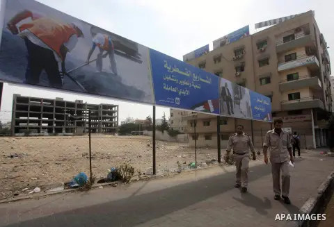 Palestinians walk pass a street placard reads in Arabic "Thank Qatar for fit promise" in Gaza city on October 21, 2012. A Qatari delegation headed by Ambassador Mohammed al-Emadi has arrived in Gaza through the Rafah cro...