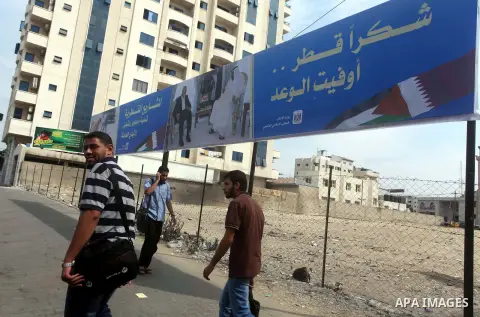Palestinians walk pass a street placard reads in Arabic "Thank Qatar for fit promise" in Gaza city on October 21, 2012. A Qatari delegation headed by Ambassador Mohammed al-Emadi has arrived in Gaza through the Rafah cro...