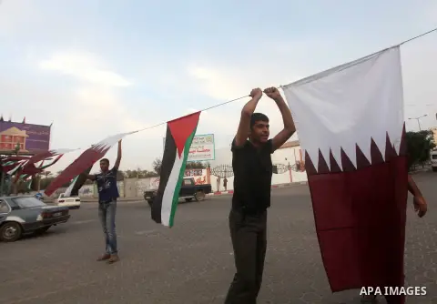 Palestinians carry the Qatari and Palestinian (red,black,white, green) flags in Gaza City on October 21, 2012, the day before the Emir of Qatar's official visit to the strip. Emir of Qatar Hamad bin Khalifa Al Thani visi...