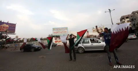 Palestinians carry the Qatari and Palestinian (red,black,white, green) flags in Gaza City on October 21, 2012, the day before the Emir of Qatar's official visit to the strip. Emir of Qatar Hamad bin Khalifa Al Thani visi...
