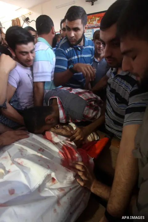 Palestinian men mourn over the body of Abderahman Abu Jalaleh, 25, during his funeral in Beit Lahia, in the northern Gaza Strip, on October 22, 2012. An Israeli air strikes killed two Gaza militants as they clashed with...
