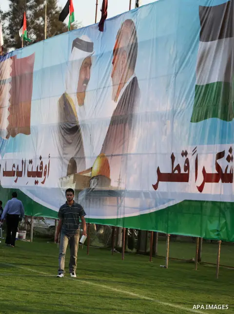 Palestinians attach posters of Hamas prime minister Ismail Haniya and Qatar's Emir Sheikh Hamad bin Khalifa al-Thani in Gaza city on October 22, 2012. The Qatari emir will visit Gaza on October 23 in the first such visit...