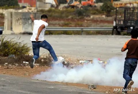 Palestinians run for cover from tear gas fired by Israeli security forces outside Israel's Ofer military prison, near the West Bank city of Ramallah, on October 22, 2012, following a demonstration in support of Palestini...