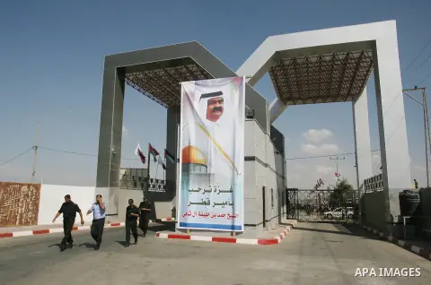 Members of Hamas' security forces stand guard near a banner depicting the Emir of Qatar Sheik Hamad bin Khalifa al-Thani in Rafah in the southern Gaza Strip October 23, 2012. The Emir of Qatar entered the Gaza Strip on T...