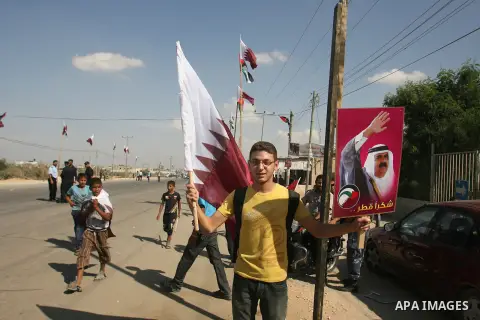 Palestinian youths wave the Qatari flag near the Rafah border crossing with Egypt during the arrival of Qatari Emir Sheikh Hamad bin Khalifa al-Thani to the Gaza Strip on October 23, 2012. The Emir of Qatar entered the G...