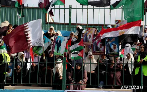 Palestinian Hamas supporters wave Qatari and Palestinian flags as others hold posters of the Emir of Qatar Sheikh Hamad bin Khalifa al-Thani, not pictured, as they wait for him to give a speech at the Palestine stadium i...