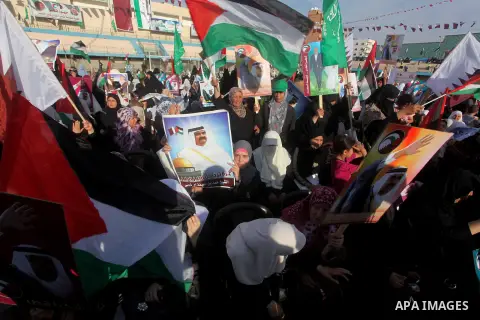 Palestinian Hamas supporters wave Qatari and Palestinian flags as others hold posters of the Emir of Qatar Sheikh Hamad bin Khalifa al-Thani, not pictured, as they wait for him to give a speech at the Palestine stadium i...