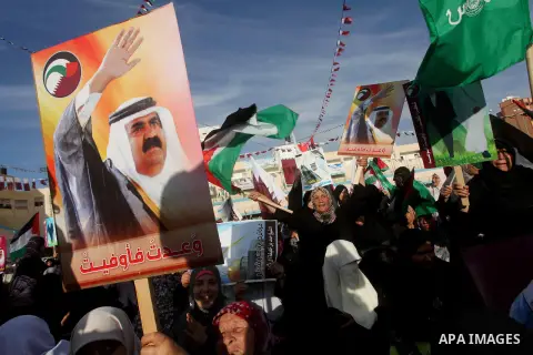 Palestinian Hamas supporters wave Qatari and Palestinian flags as others hold posters of the Emir of Qatar Sheikh Hamad bin Khalifa al-Thani, not pictured, as they wait for him to give a speech at the Palestine stadium i...