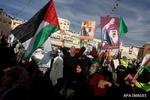 Palestinian Hamas supporters wave Qatari and Palestinian flags as others hold posters of the Emir of Qatar Sheikh Hamad bin Khalifa al-Thani, not pictured, as they wait for him to give a speech at the Palestine stadium i...