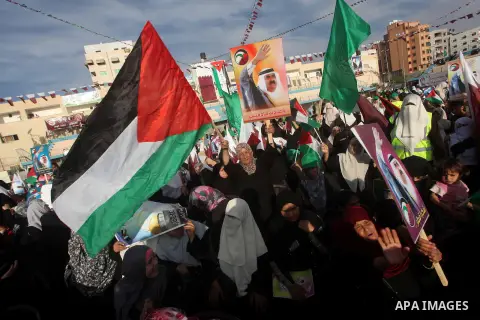 Palestinian Hamas supporters wave Qatari and Palestinian flags as others hold posters of the Emir of Qatar Sheikh Hamad bin Khalifa al-Thani, not pictured, as they wait for him to give a speech at the Palestine stadium i...