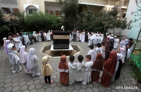 Palestinian children gather around a makeshift cube representing the holy Kaaba in Gaza City, on October 24, 2012, as part of training children how to perform Hajj pilgrimage. Muslims from around the world flood Saudi ci...