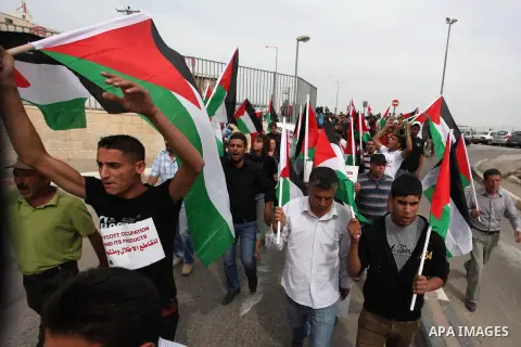 Palestinian activists hold up the Palestinian flag as they rally outside a branch of the Rami Levy supermarket which opened in Shaar Binyamin Jewish settlement close to the city of Ramallah in the Israeli occupied Palest...