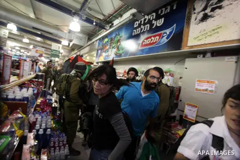 Palestinian activists hold up the Palestinian flag as they rally inside a branch of the Rami Levy supermarket which opened in Shaar Binyamin Jewish settlement close to the city of Ramallah in the Israeli occupied Palesti...