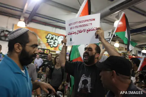 Palestinian activists hold up the Palestinian flag as they rally inside a branch of the Rami Levy supermarket which opened in Shaar Binyamin Jewish settlement close to the city of Ramallah in the Israeli occupied Palesti...