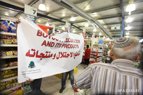 Palestinian activists hold up the Palestinian flag as they rally inside a branch of the Rami Levy supermarket which opened in Shaar Binyamin Jewish settlement close to the city of Ramallah in the Israeli occupied Palesti...