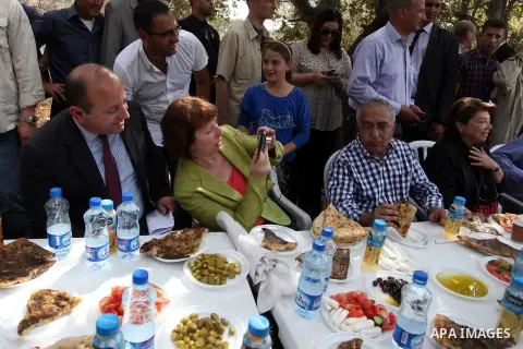 Palestinian Prime Minister Salam Fayyad and EU Foreign Policy chief Catherine Ashton help Palestinian farmers during harvesting olives in the West Bank village of Ras Karkar near Ramallah, on October 25, 2012. Photo by I...