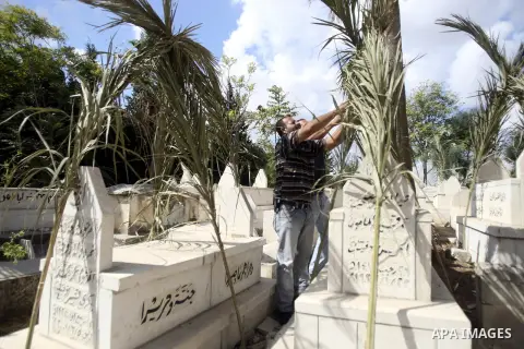 Palestinians put palm fronds on the graves of their relatives ahead of Muslim festival of Eid al-Adha, in the West Bank city of Nablus, on October 25, 2012. Muslims around the world prepare to celebrate Eid Al-Adha, whic...