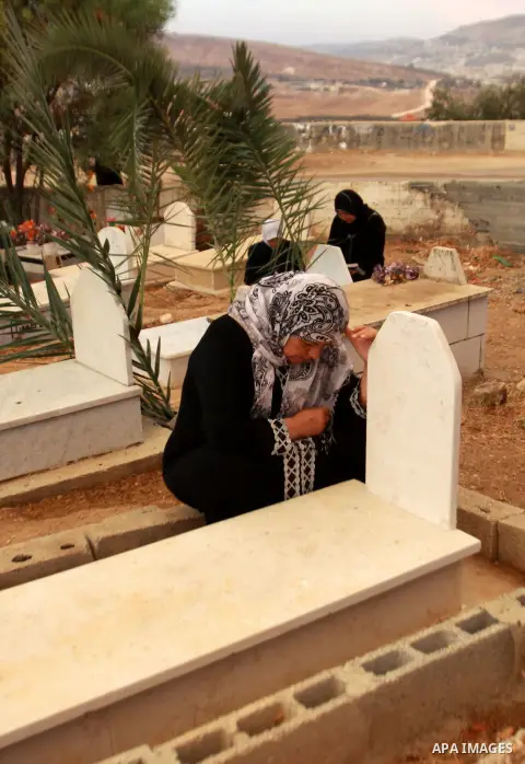 Palestinians visit the graves of relatives at a cemetery in the West Bank city of Nablus on the first day of Eid al-Adha, on October 26, 2012 as Muslims worldwide commemorate Eid al-Adha, or the Feast of the Sacrifice, m...