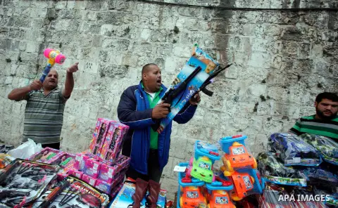 A Palestinian vendor brandishes a toy weapon outside al-Aqsa Mosque compound in Jerusalem's Old city, on the first day of Eid al-Adha October 26, 2012. Muslims around the world celebrate Eid al-Adha to mark the end of th...