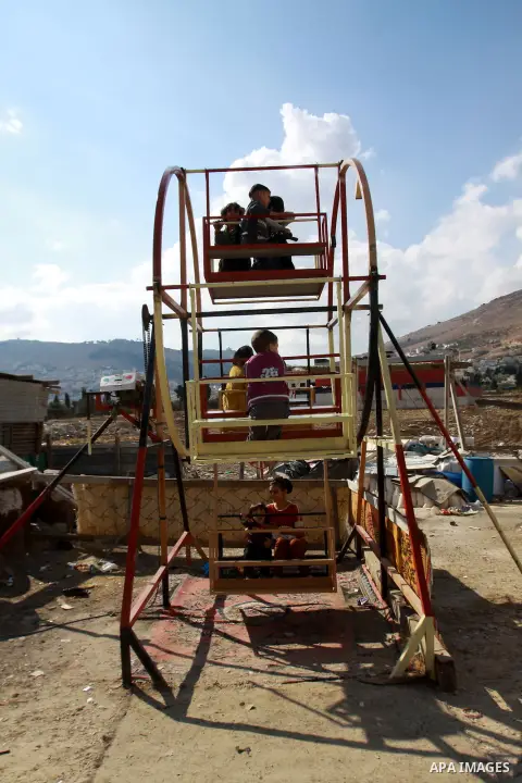 Palestinian children enjoy a ride at an amusement park during the second day of Eid al-Adha in the West Bank city of Nablus, oct 27, 2012. Muslims around the world celebrate Eid-al-Adha, marking the end of the haj, by sl...