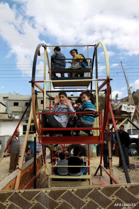 Palestinian children enjoy a ride at an amusement park during the second day of Eid al-Adha in the West Bank city of Nablus, oct 27, 2012. Muslims around the world celebrate Eid-al-Adha, marking the end of the haj, by sl...