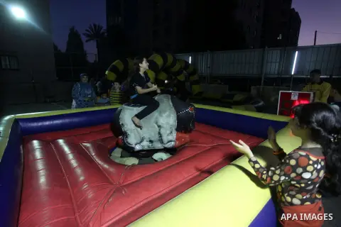 Palestinian children enjoy a ride at an amusement park during the second day of Eid al-Adha in the West Bank city of Ramallah, oct 27, 2012. Muslims around the world celebrate Eid-al-Adha, marking the end of the haj, by...