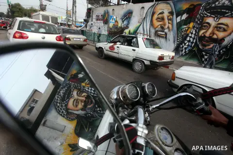 Palestinians passe by a mural depicting late Palestinian leader Yasser Arafat in Gaza City on Oct. 31, 2012. Palestinian authorities confirmed the November timetable to exhume the remains of former Palestinian leader Yas...