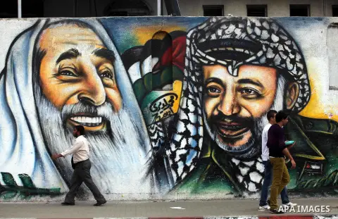 Palestinians passe by a mural depicting late Palestinian leader Yasser Arafat in Gaza City on Oct. 31, 2012. Palestinian authorities confirmed the November timetable to exhume the remains of former Palestinian leader Yas...