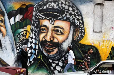 Palestinians passe by a mural depicting late Palestinian leader Yasser Arafat in Gaza City on Oct. 31, 2012. Palestinian authorities confirmed the November timetable to exhume the remains of former Palestinian leader Yas...