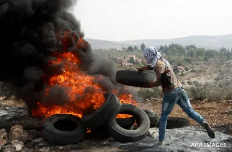 A Palestinian protester burns tires during clashes with Israeli soldiers following a demonstration marking the anniversary of Balfour Declaration, in the village of Kfar Qaddum, near the West Bank city of Nablus on Novem...