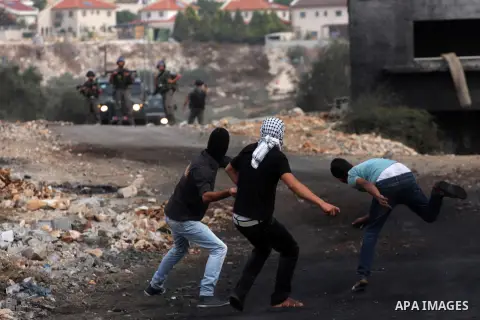 Palestinian protesters throw stones on towards Israeli soldiers during clashes following a demonstration marking the anniversary of Balfour Declaration, in the village of Kfar Qaddum, near the West Bank city of Nablus on...