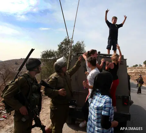 A Palestinian boy makes victory signs as he stands on an Israeli army vehicle during a protest against the confiscation of Palestinian land by Israel in the West Bank village of Nabi Saleh near Ramallah on November 2, 20...