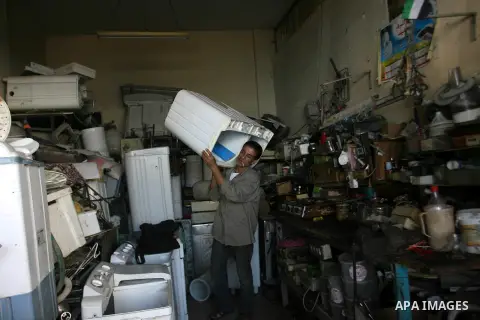 A Palestinian man repairs a washer at his workshop in Rafah southern in Gaza City on November 6, 2012. Photo by Eyad Al Baba