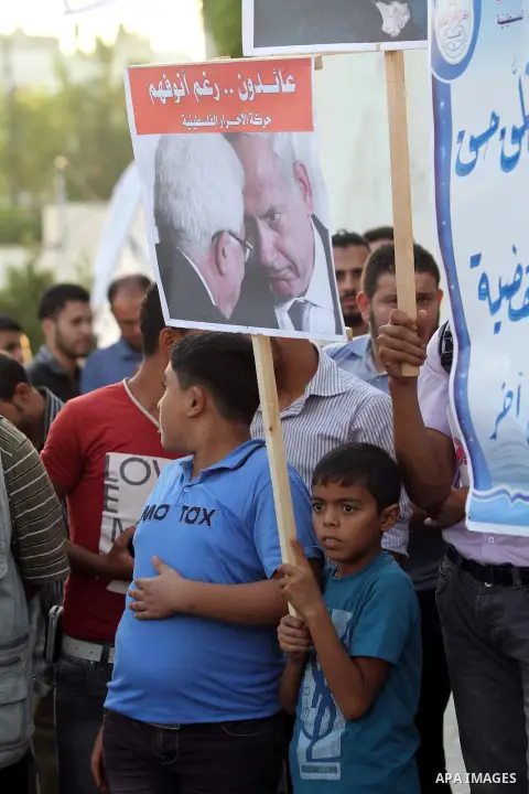 El-Ahrar party supporters carry placards and posters of Palestinian President Mahmoud Abbas with Israeli leaders during a demonstration in Gaza city on November 6, 2012. Protestors gathered to express their anger towards...