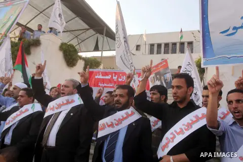El-Ahrar party supporters carry placards and posters of Palestinian President Mahmoud Abbas with Israeli leaders during a demonstration in Gaza city on November 6, 2012. Protestors gathered to express their anger towards...