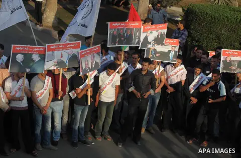El-Ahrar party supporters carry placards and posters of Palestinian President Mahmoud Abbas with Israeli leaders during a demonstration in Gaza city on November 6, 2012. Protestors gathered to express their anger towards...