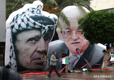 Palestinians walk pass a mural of the late Yasser Arafat and current Palestinian President Mahmoud Abbas during the eighth anniversary of the death of the late leader Yasser Arafat, in the West Bank city of Nablus on Nov...
