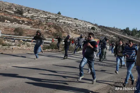 Palestinian demonstrators run cover from tear gas during clashes against Israel's operations in Gaza Strip, outside Ofer, an Israeli military prison near the West Bank city of Ramallah, Thursday, Nov. 15, 2012. Meanwhile...